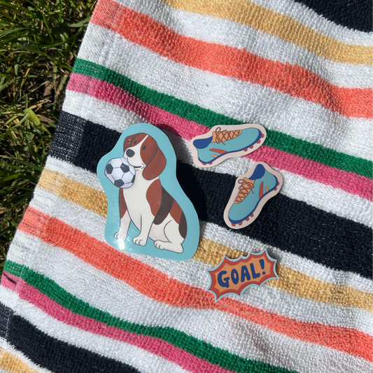 Colorful striped towel with dog stickers on grass