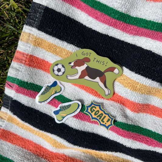 Colorful striped towel with sports-themed stickers on grass