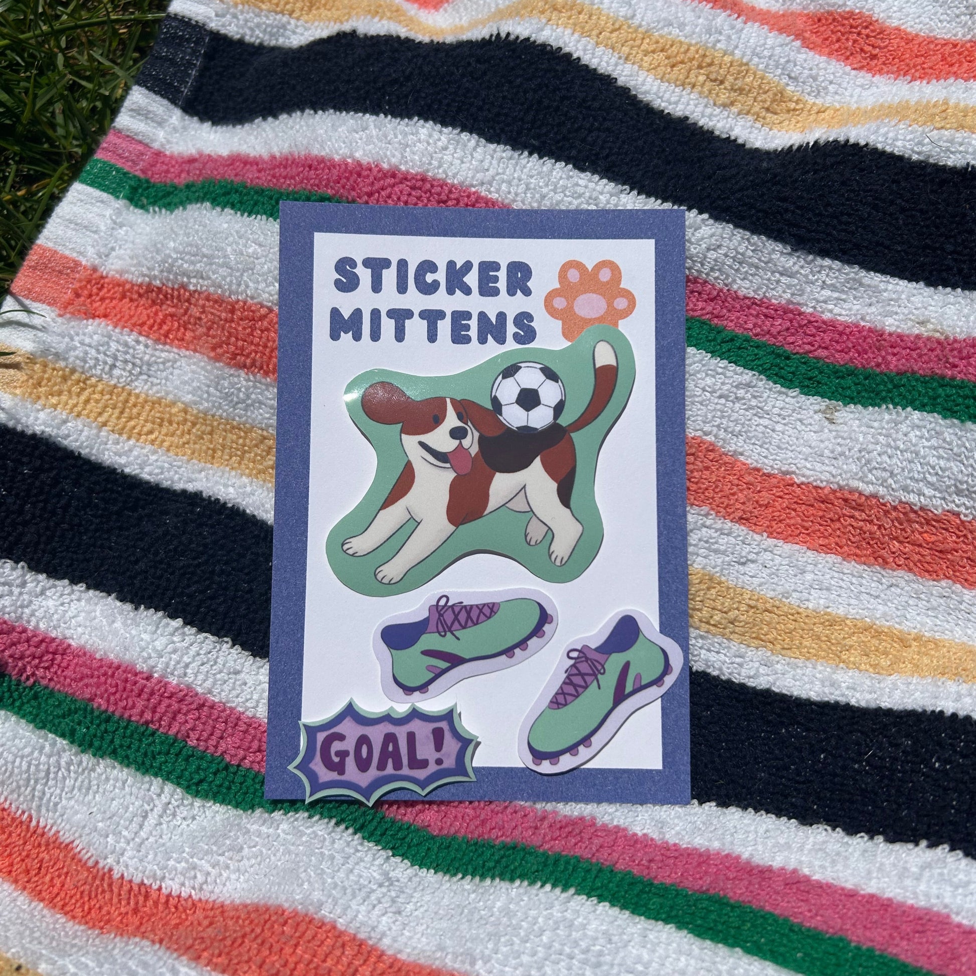 sticker of dog playing football with 'Sticker Mitten' branding on a striped towel
