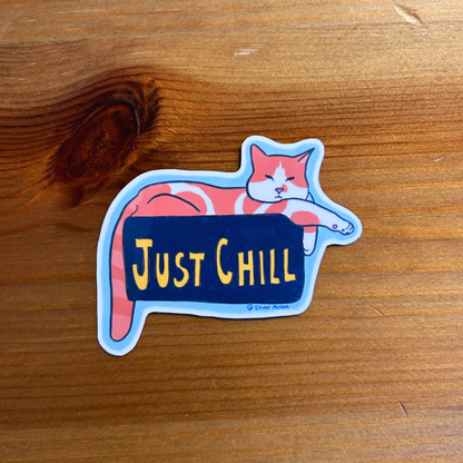 Sticker of a cat lying down with 'Just Chill' text on a wooden surface